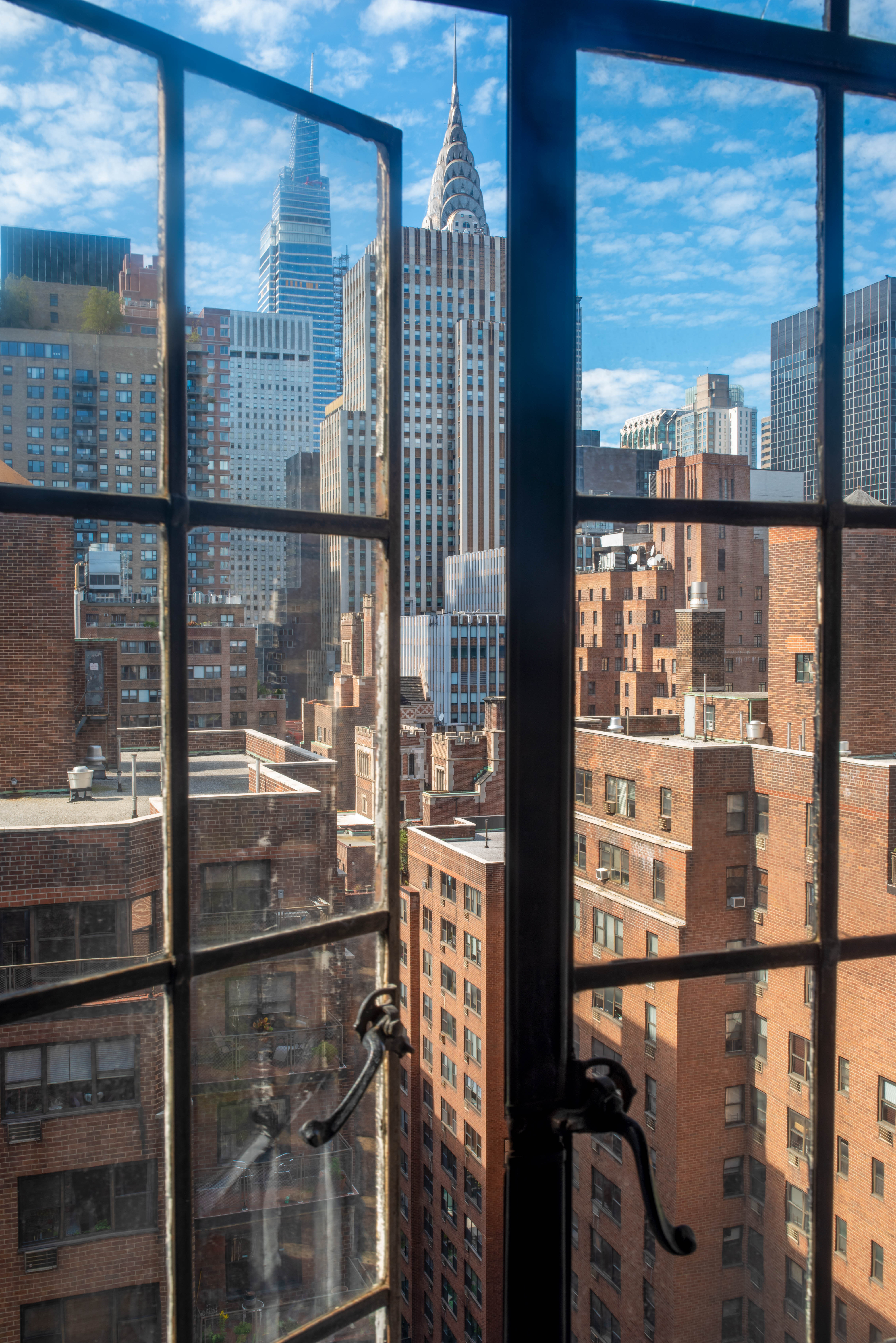 View of Manhattan skyline including Chrysler Building through open windows of high-rise office building